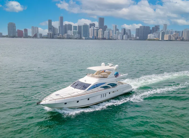 The Image of 2004 Azimut 62 yacht cruising near a city skyline on a sunny day. - 0