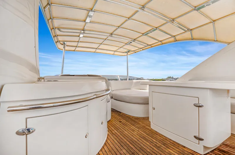 Slide: The Image of 2004 Azimut 62 yacht deck with seating and canopy under blue sky. - 26