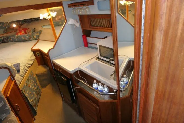 Slide: The Image of 1988 Sea Ray 300 Weekender cabin interior with kitchenette, sink, and bed. - 10