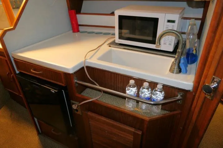 Slide: The Image of 1988 Sea Ray 300 Weekender galley with sink, microwave, and mini fridge. - 11