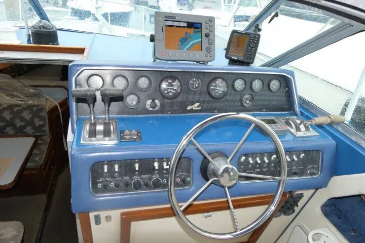 Slide: The Image of 1988 Sea Ray 300 Weekender helm with blue dashboard, steering wheel, and navigation equipment. - 16