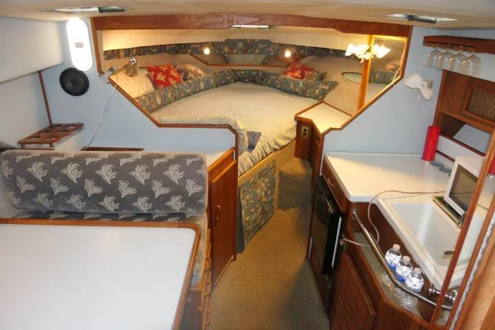 Slide: The Image of 1988 Sea Ray 300 Weekender cabin interior with cozy seating, kitchenette, and sleeping area. - 2