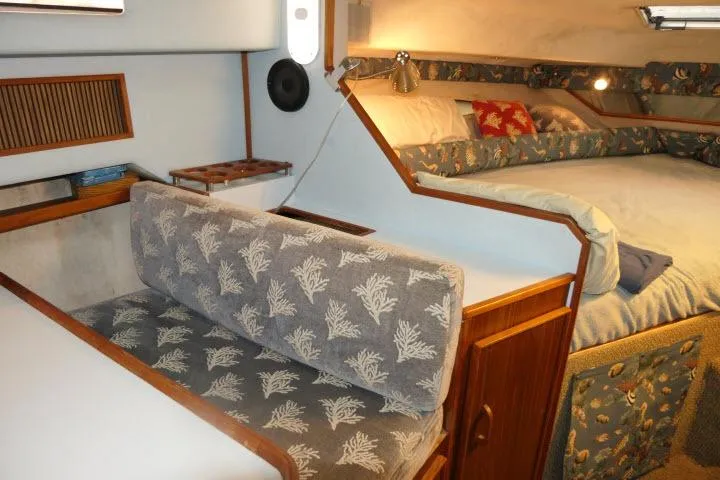 Slide: The Image of 1988 Sea Ray 300 Weekender interior with cozy seating and bed, featuring nautical decor. - 6