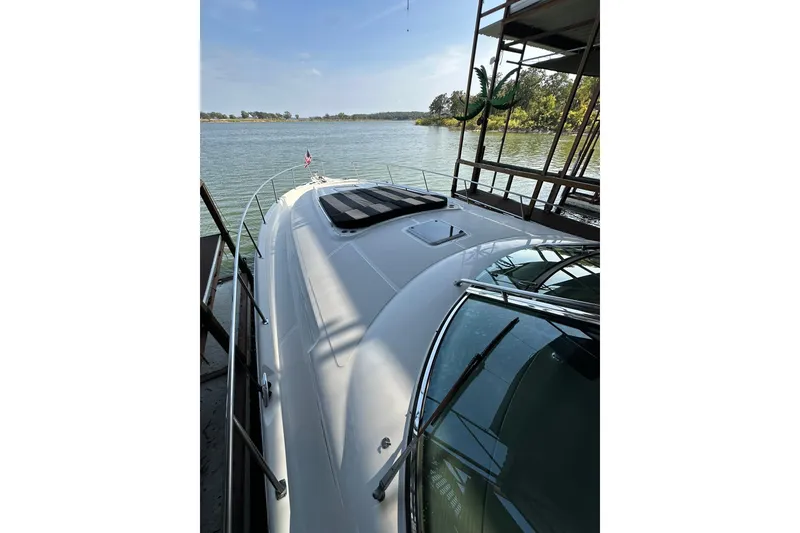 Slide: The Image of 2003 Sea Ray 460 Sundancer yacht docked by a serene lake under clear skies. - 17