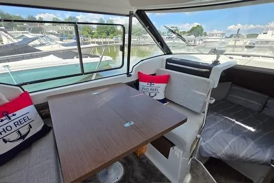 Slide: The Image of 2024 Jeanneau NC Weekender 795 Series 2 interior with table, seating, and marina view. - 10