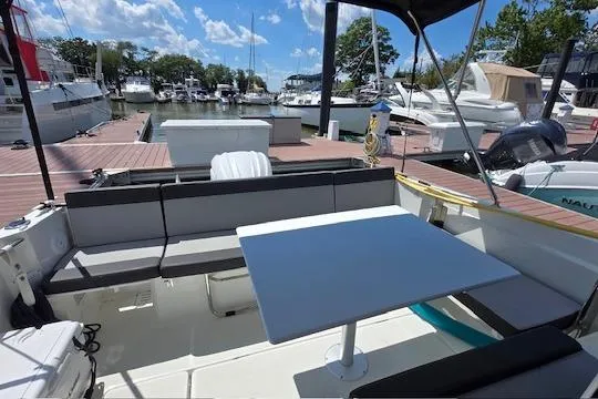 Slide: The Image of 2024 Jeanneau NC Weekender 795 Series 2 boat interior with seating and table at marina. - 6