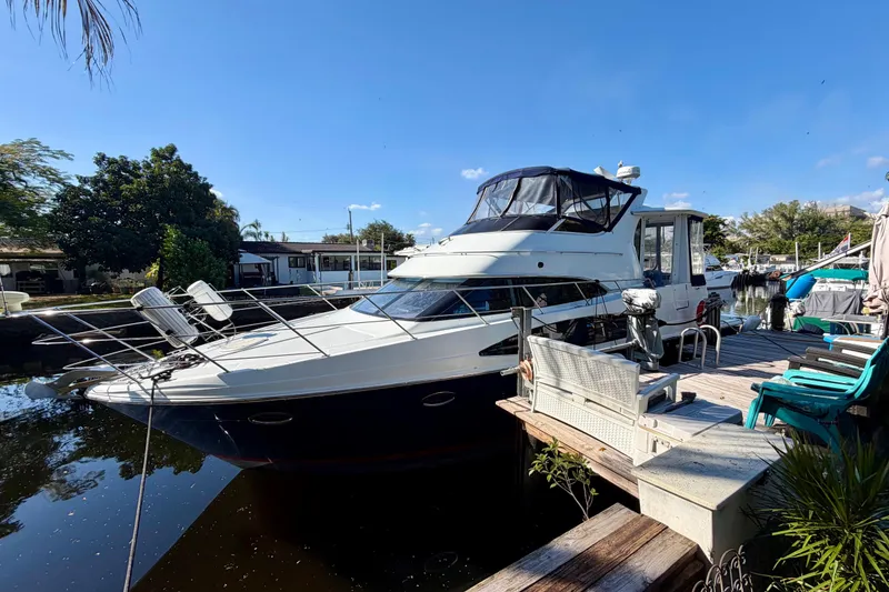 Slide: The Image of 2002 Carver 444 Cockpit Motor Yacht docked by a sunny waterfront. - 1