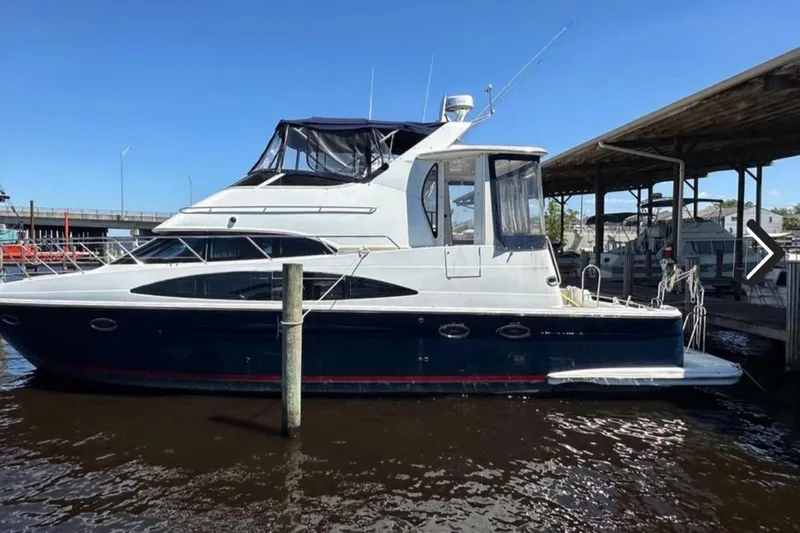 The Image of 2002 Carver 444 Cockpit Motor Yacht docked at marina under clear blue sky. - 0