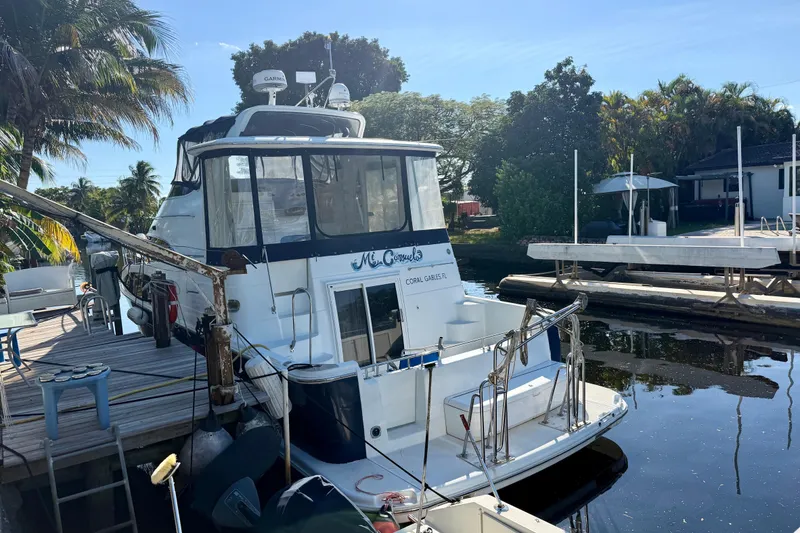 Slide: The Image of 2002 Carver 444 Cockpit Motor Yacht docked by a tropical waterfront. - 2