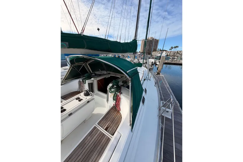 Slide: The Image of 1995 Beneteau Oceanis 351 sailboat docked, featuring green canopy and wooden deck. - 21