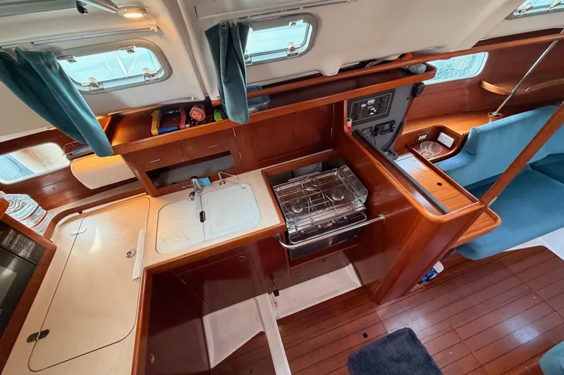Slide: The Image of Interior of a 1995 Beneteau Oceanis 351 sailboat, featuring a compact kitchen and seating area. - 34