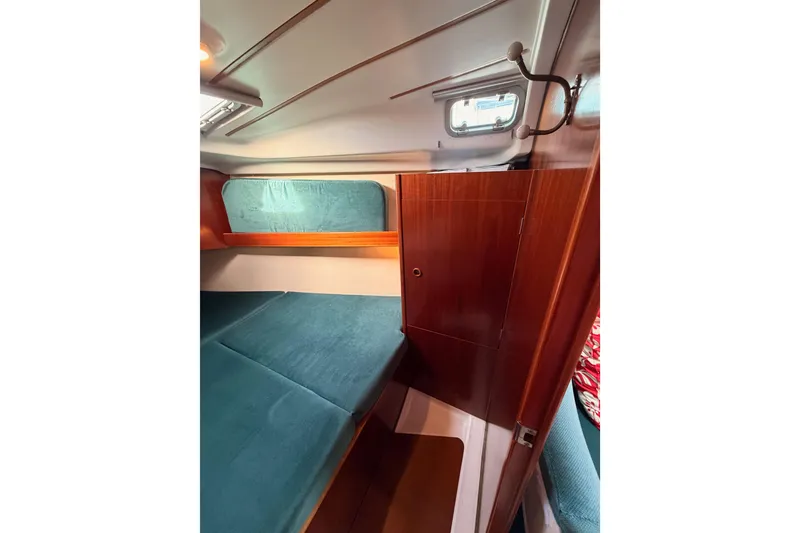 Slide: The Image of Interior cabin of 1995 Beneteau Oceanis 351 sailboat with teal cushions and wooden paneling. - 54