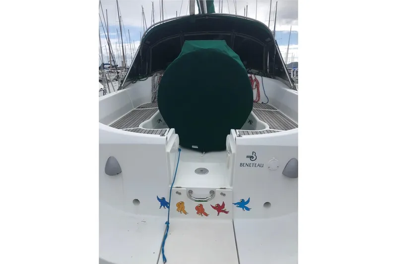 Slide: The Image of 1995 Beneteau Oceanis 351 sailboat stern view with colorful decals and covered wheel. - 74