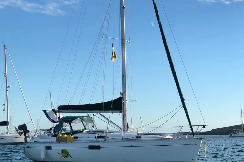 Slide: The Image of 1995 Beneteau Oceanis 351 sailboat anchored in calm waters under a clear blue sky. - 77