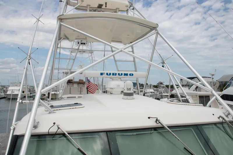 Slide: The Image of 2016 Henriques 42 Express Hardtop boat with tower and American flag in marina. - 15
