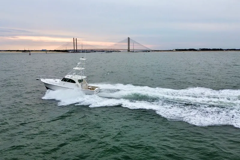 Slide: The Image of 2016 Henriques 42 Express Hardtop cruising on open water near a bridge at sunset. - 2