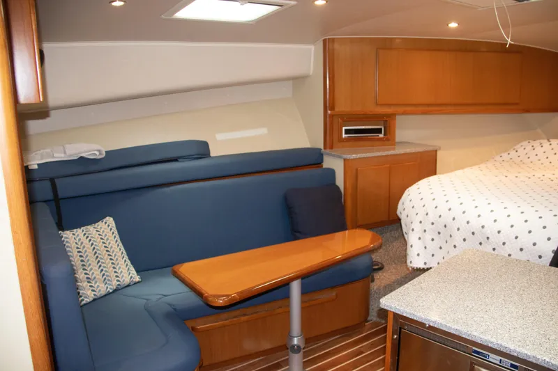 Slide: The Image of 2016 Henriques 42 Express Hardtop interior with blue seating, wooden table, and cozy bed. - 21
