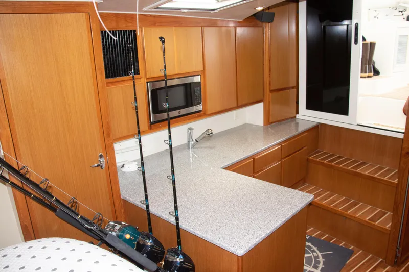 Slide: The Image of 2016 Henriques 42 Express Hardtop interior with wooden cabinetry and fishing rods. - 22