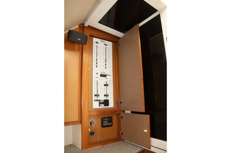 Slide: The Image of Electrical panel inside 2013 Henriques 42 Express Hardtop boat, featuring open cabinet doors. - 27