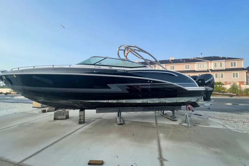 Slide: The Image of 2019 Formula 310 FX Bowrider boat on dry dock, sleek black design, residential background. - 12