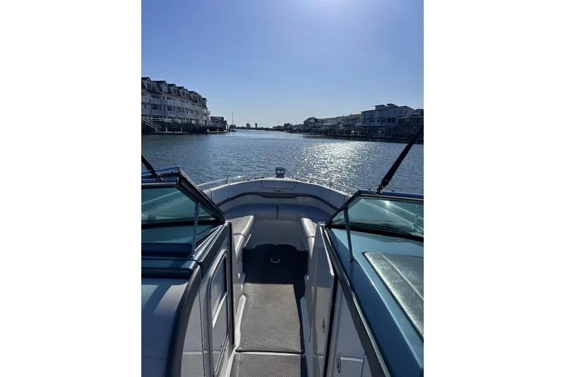 Slide: The Image of 2019 Formula 310 FX Bowrider cruising on a sunny waterfront with houses. - 6