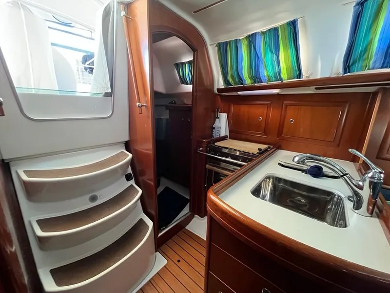 Slide: The Image of Interior of 2005 Beneteau 323 sailboat with wooden cabinetry and compact kitchen area. - 33