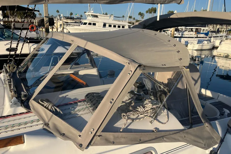 Slide: The Image of 2005 Beneteau 323 sailboat with cockpit cover, docked in a marina. - 42