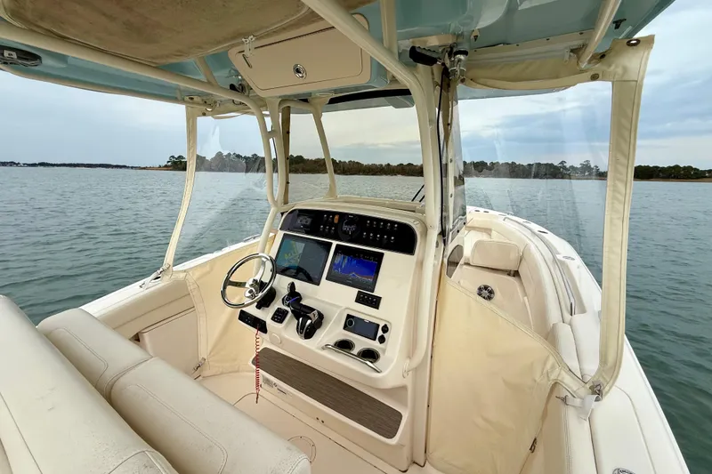 Slide: The Image of 2022 Grady-White Canyon 271 boat interior with navigation equipment on calm water. - 22