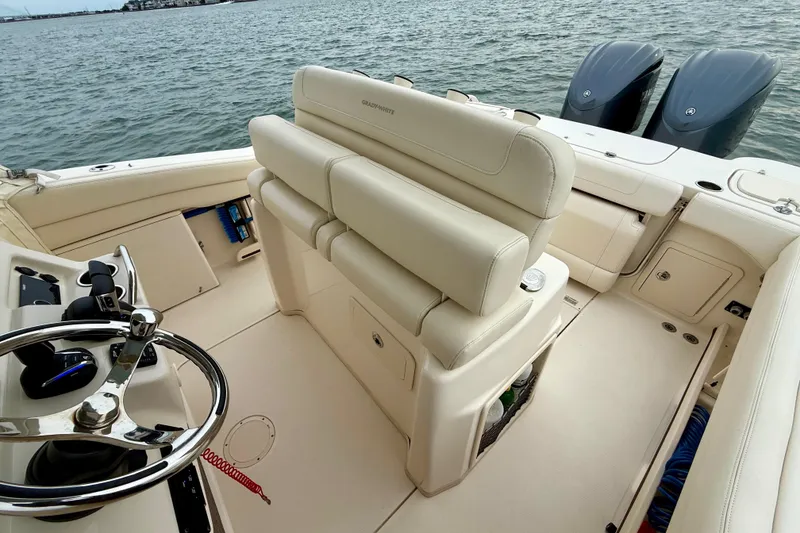 Slide: The Image of 2022 Grady-White Canyon 271 boat interior with helm and seating, on calm water. - 31