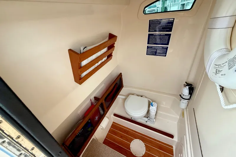 Slide: The Image of 2022 Grady-White Canyon 271 boat interior with toilet, wooden flooring, and safety equipment. - 46