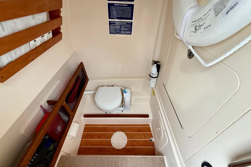 Slide: The Image of 2022 Grady-White Canyon 271 boat interior with toilet, wooden flooring, and safety equipment. - 47