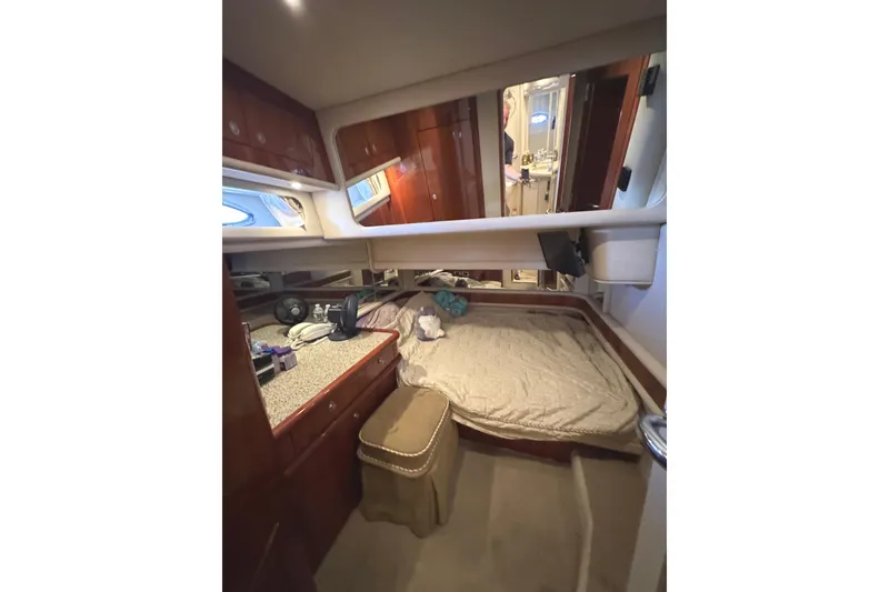 Slide: The Image of 2004 Sea Ray 560 Sedan Bridge cabin interior with bed, wooden cabinets, and mirror. - 29