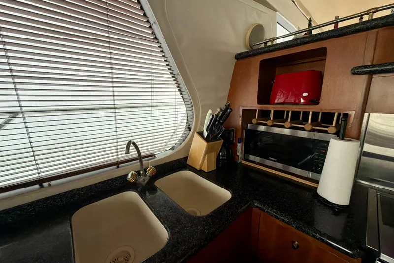 Slide: The Image of Interior of 1999 Carver 530 Voyager Pilothouse kitchen with sink, microwave, and blinds. - 19