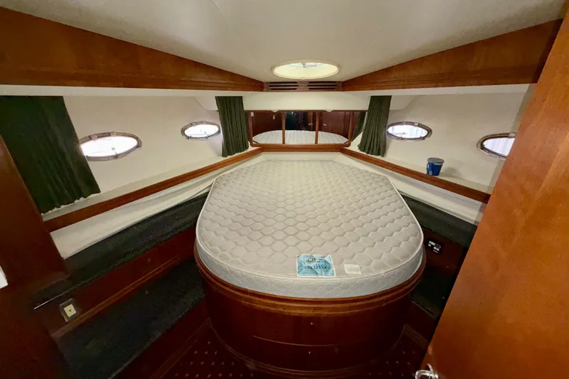 Slide: The Image of 1999 Carver 530 Voyager Pilothouse bedroom with oval mattress and wooden interior. - 23