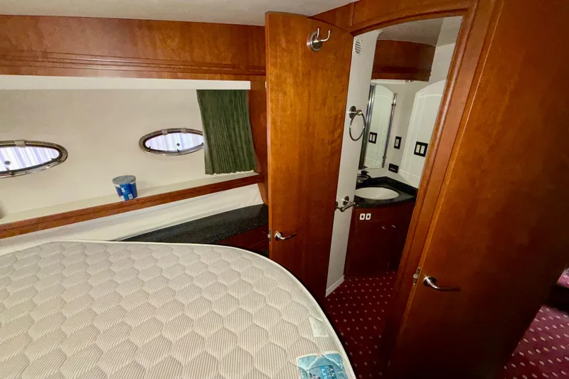 Slide: The Image of 1999 Carver 530 Voyager Pilothouse cabin with bed, portholes, and bathroom entrance. - 24