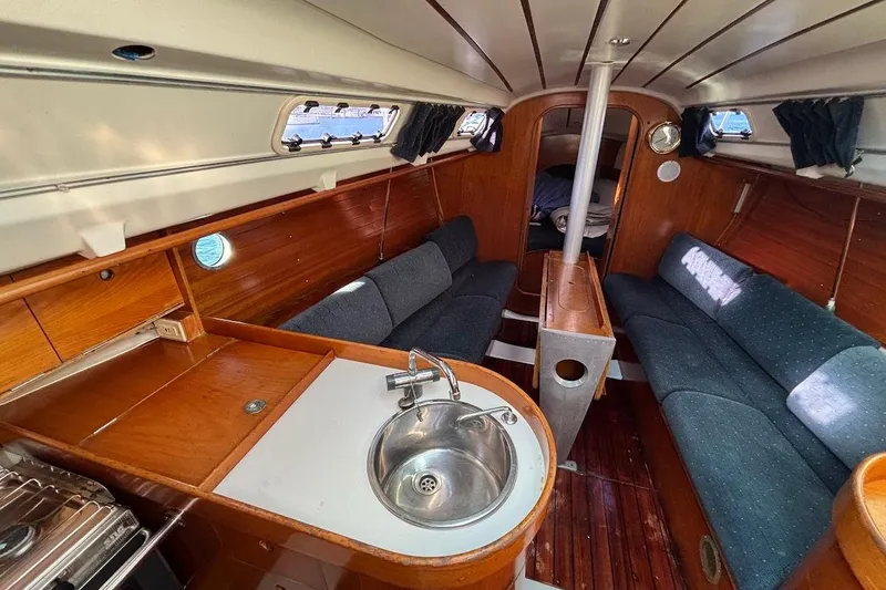Slide: The Image of Interior of 1993 Beneteau First 310 sailboat with cozy seating and compact kitchen area. - 14