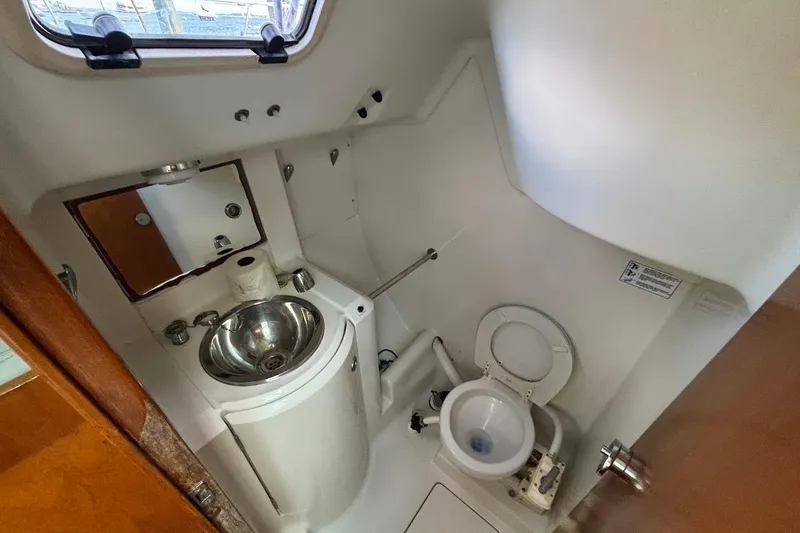 Slide: The Image of Compact bathroom in a 1993 Beneteau First 310 sailboat, featuring a sink and toilet. - 22