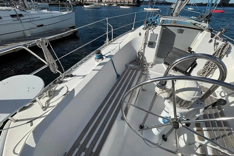Slide: The Image of Cockpit view of a 1993 Beneteau First 310 sailboat, featuring steering wheel and ropes. - 4