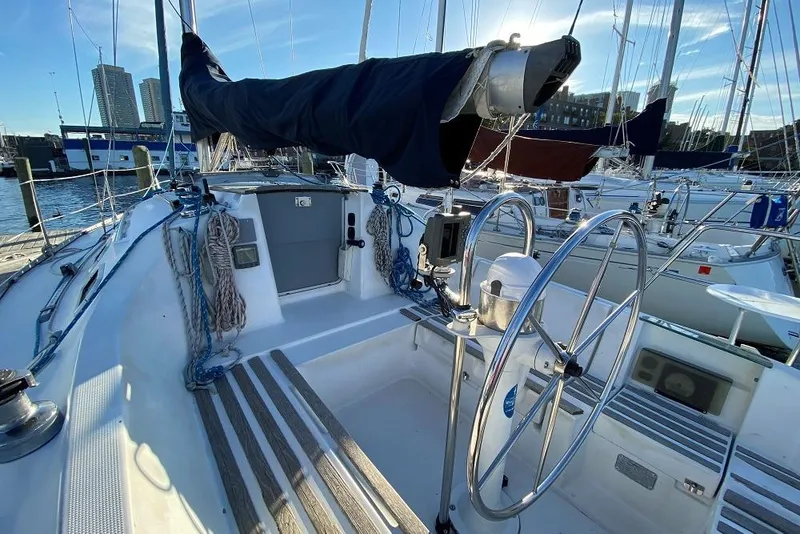 Slide: The Image of Cockpit of 1993 Beneteau First 310 sailboat with dual steering wheels and marina view. - 5