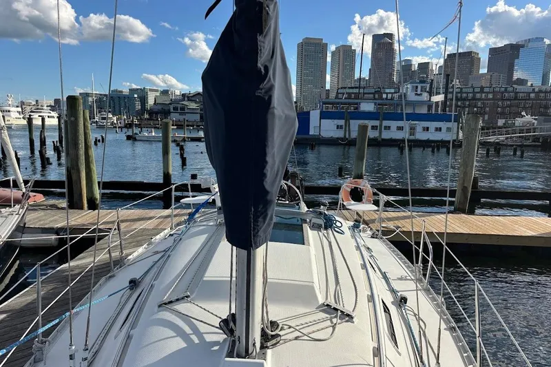 Slide: The Image of 1993 Beneteau First 310 sailboat docked in a marina with city skyline background. - 7