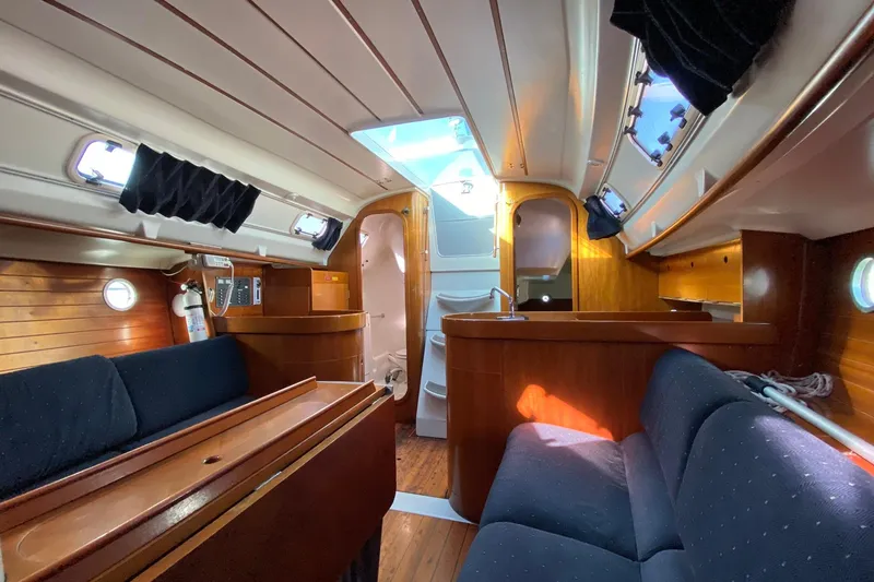 Slide: The Image of Interior of a 1993 Beneteau First 310 sailboat, featuring wood paneling and seating. - 8
