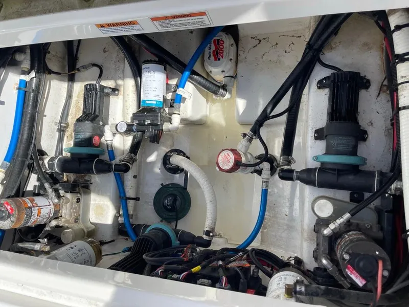 Slide: The Image of 2019 Blackfin 272 CC boat engine compartment with various pumps and hoses. - 32