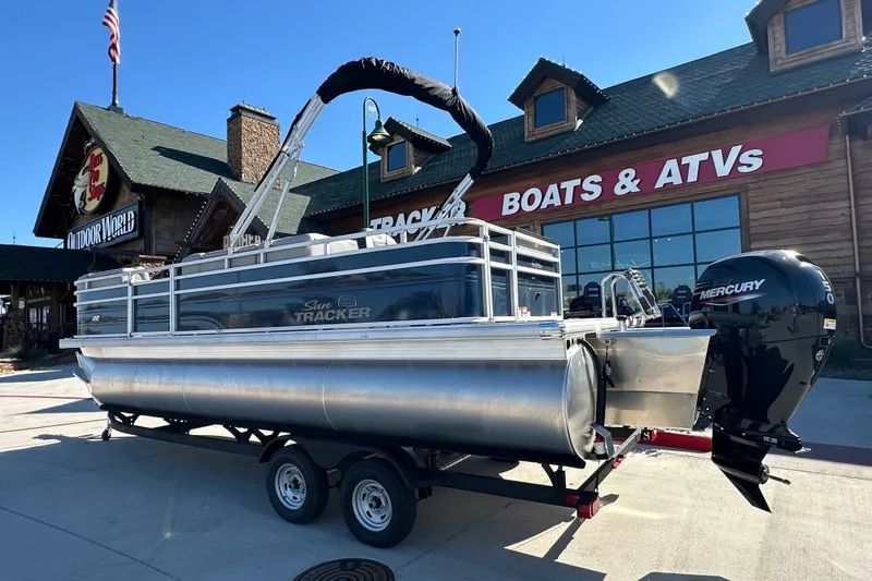 The Image of 2026 Sun Tracker SportFish 22 XP3 pontoon boat displayed outside a dealership. - 1