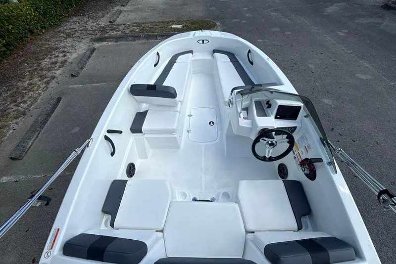 Slide: The Image of 2026 Tahoe T16 boat interior with seating and steering console, parked on pavement. - 3