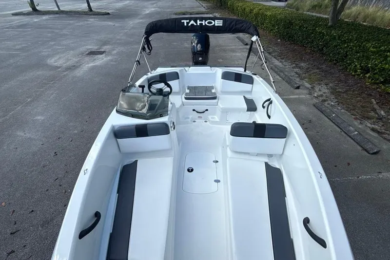 Slide: The Image of 2026 Tahoe T16 boat with seating, steering wheel, and canopy in a parking area. - 4
