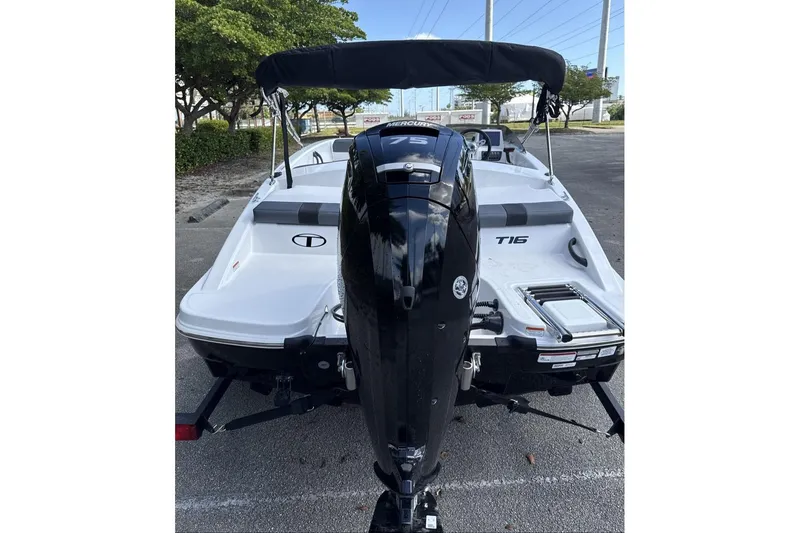 Slide: The Image of 2026 Tahoe T16 boat with outboard motor, parked on pavement under a canopy. - 6