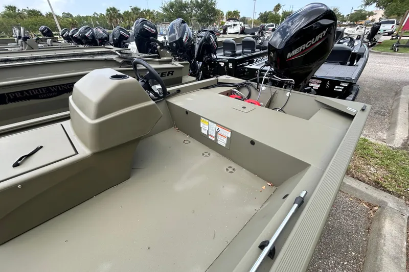 Slide: The Image of 2026 Tracker Grizzly 1648 SC boat with Mercury engine, parked outdoors. - 3