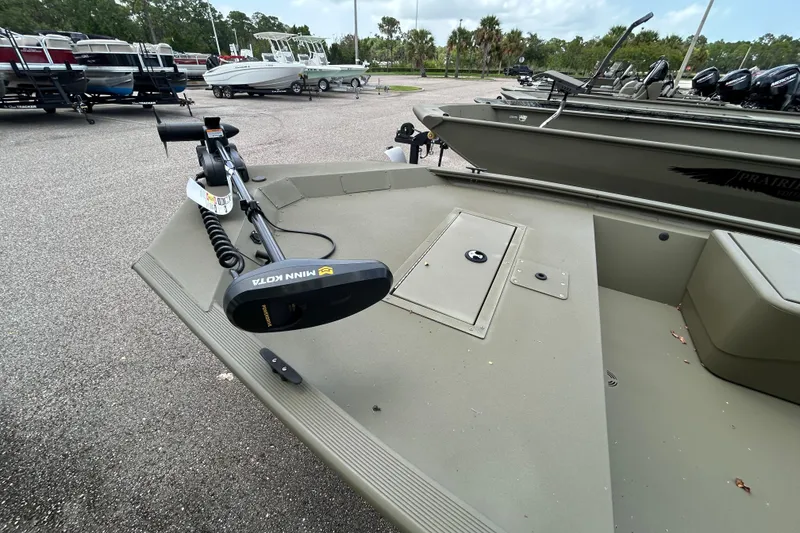 Slide: The Image of 2026 Tracker Grizzly 1648 SC boat with Minn Kota trolling motor in a parking lot. - 4