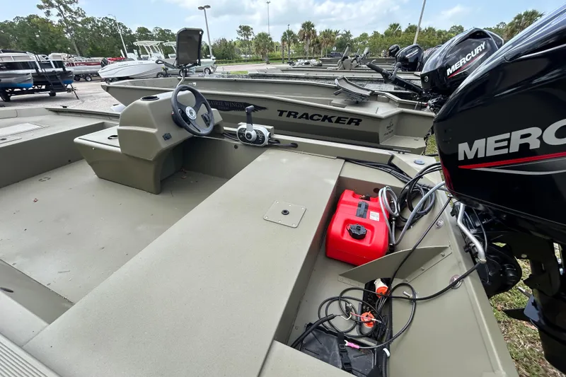 Slide: The Image of 2026 Tracker Grizzly 1648 SC boat with Mercury engine, parked outdoors. - 2