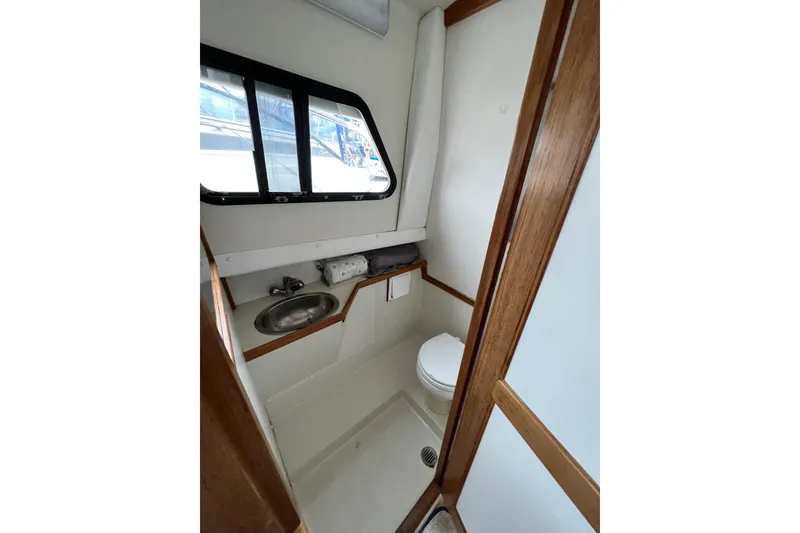 Slide: The Image of 2001 Skipjack 262 Flybridge boat bathroom with sink, toilet, and window. - 13